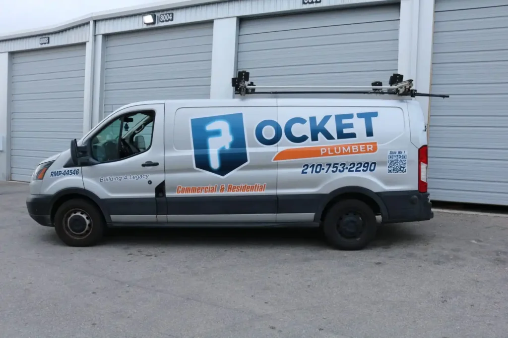 A white "Pocket Plumber" service van with a large wrench logo, phone number, and "Commercial & Residential" text is parked next to a building