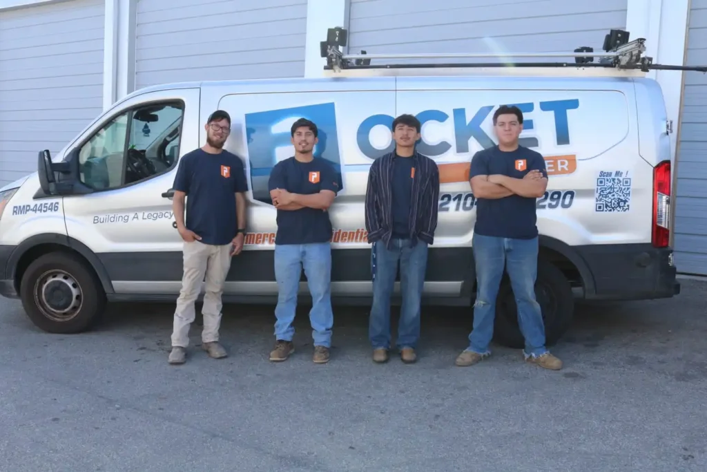 Four young men in "Pocket Plumber" t-shirts and jeans pose in front of a white service van, some with crossed arms